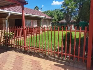 a red fence in front of a house at Savannah Guest House Mafikeng in Mahikeng