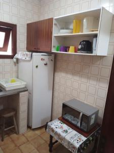 a kitchen with a white refrigerator and a table with a microwave at Apartamento para Temporada Ubatuba in Ubatuba
