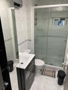 a bathroom with a toilet and a glass shower at Habitaciones privadas in Madrid