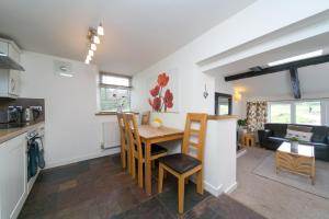a kitchen and living room with a table and chairs at Harrison's Cottage in Llandegla