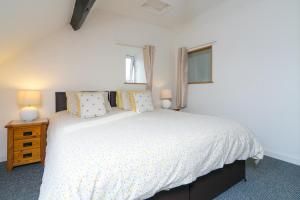 a bedroom with a white bed and two windows at Harrison's Cottage in Llandegla