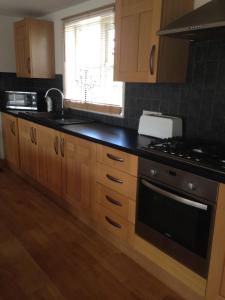 a kitchen with wooden cabinets and a black counter top at Rebels Hide -Self check in apartment in Penrith +17 photos