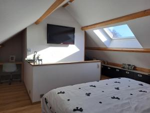 a bedroom with a bed and a tv on the wall at Au Sarseyis - studio d'hôtes - studio équestre in Robertville