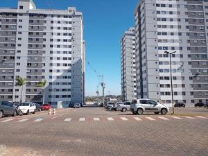 a parking lot with cars parked in front of tall buildings at Apartamento Duplex em Condomínio com portaria in Uberaba
