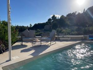 eine Terrasse mit zwei Stühlen und einem Swimmingpool in der Unterkunft Villa Centenary Goose in Korčula