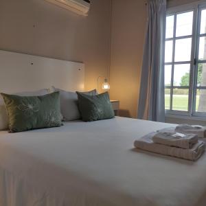 una camera da letto con un grande letto bianco con una finestra di Alojamiento Dimar a Villa Elisa Altre 36 foto