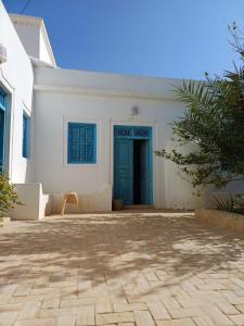 a white building with a blue door on it at Houch Mejine in Medjine