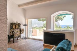 a living room with a fireplace and a large window at villa les nefliers vue panoramique mer et plage à pied in Cassis