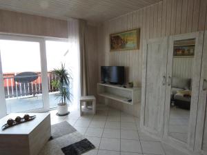 a living room with a television and a balcony at Haus Evelyn in Rheinsberg +4 photos