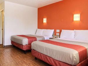 two beds in a hotel room with orange walls at Motel 6-Bismarck, ND in Bismarck