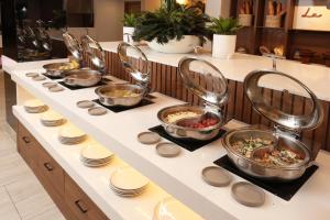 a buffet line with bowls and plates of food at voco Hermosillo by IHG in Hermosillo +85 photos