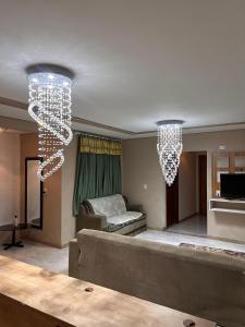 a living room with two chandeliers and a couch at Suíte por do sol 1 privada casa compartilhada in Xangri-lá