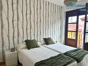 two beds in a room with trees on the wall at Dos Torres Pilar Suites- balcones con vistas a la ciudad in Zaragoza
