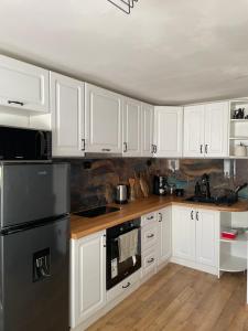 a kitchen with white cabinets and a black refrigerator at Къща за гости Клонката in Dŭlbok Dol