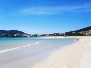 a sandy beach with the ocean and buildings in the background at Apartamento Playa Langosteira in Fisterra