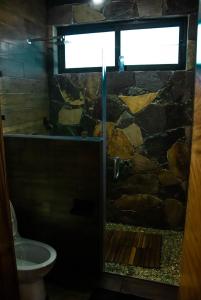 a bathroom with a shower with a stone wall at Modern and cozy cabana in La Cofradía