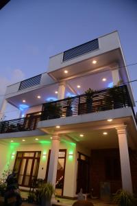 a white house with a balcony with green lights at Villa KN in Ambalangoda
