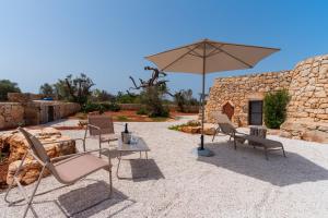 a group of chairs and an umbrella on a patio at Trullo dei Beneficati By Vivimy in Taviano