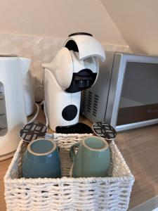 een mand met kopjes en een koffiezetapparaat op een tafel bij La Planque des Halles - Hyper Centre - Bureau in Troyes