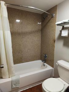 a bathroom with a white tub and a toilet at American Inn & Suites By Capital O Victoria US-59 in Victoria