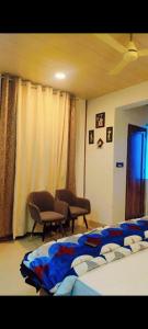 a bedroom with a bed and two chairs and curtains at Unnati Guest House in Vrindāvan