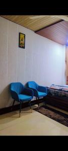 a room with three blue chairs and a bed at Unnati Guest House in Vrindāvan