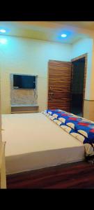 a bedroom with a large bed with a tv on the wall at Unnati Guest House in Vrindāvan