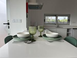 a table with two plates and glasses on it at Quinta das Pedreiras Lux in Pico da Pedra