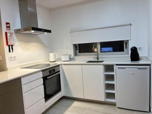 a small kitchen with white cabinets and a sink at Quinta das Pedreiras Lux in Pico da Pedra
