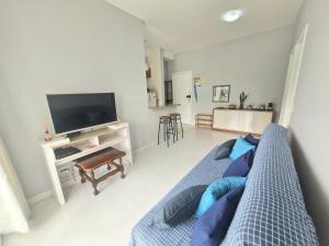 Una sala de estar con un sofá azul y un televisor. en Charmoso com varanda - Ar condicionado - 1 Vaga, en Santos