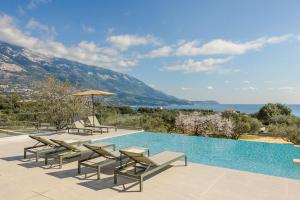 una piscina con sedie a sdraio e una piscina di Villa Oro di Agathera Kefaloniaprivatevillas ad Argostoli