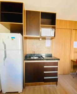 een keuken met een witte koelkast en houten kasten bij Flat Comfort Hotel Taguatinga 906 in Brasilia