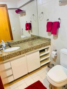 een badkamer met een wastafel, een toilet en een spiegel bij Flat Comfort Hotel Taguatinga 906 in Brasilia