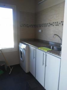 a kitchen with a sink and a washing machine at Cabaña Las Retamas in San Andres de las Sierras