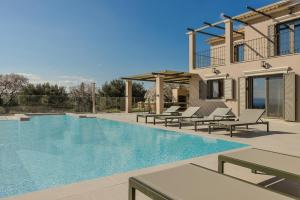 una piscina con sedie e una casa di Villa Oro di Agathera Kefaloniaprivatevillas ad Argostoli