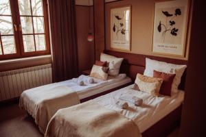 two beds in a hotel room with dolls on them at Dworek in Kolbuszowa