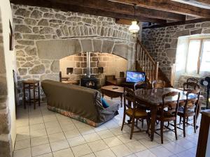a living room with a table and a stone fireplace at Gîte de France à Darazac 2 épis - Gîte de France 2 personnes MAE-5181 in Darazac
