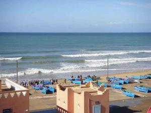 a beach with blue chairs and the ocean at Centre D'estivage Imi Ouaddar in Agadir nʼ Aït Sa