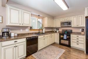 a kitchen with white cabinets and a black dishwasher at River Run Getaway Private Dock Pet Friendly Kayaks in Bend