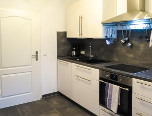 a kitchen with white cabinets and a stove top oven at Komfortzone in Brietlingen