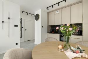 a kitchen with a table with a vase of flowers on it at Porta Maria - z basenem - Easy- Rent Apartments in Dziwnów +39 photos