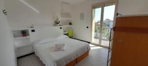 a white bedroom with a bed and a large window at Hotel Marbella in Cervia