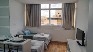 een woonkamer met 2 bedden en een televisie bij Flat Centro de Curitiba Rua 24 horas in Curitiba