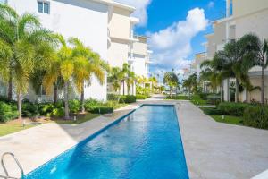 Xeliter Playa Coral, Bavaro في بونتا كانا: حمام سباحة أمام مبنى به أشجار نخيل