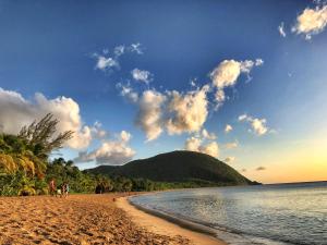 a group of people walking on a beach at Cottage Honoré Paradise in Deshaies