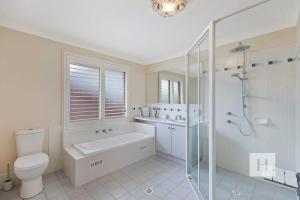 a bathroom with a toilet and a shower and a sink at Sunset Lakehouse in Toukley +8 photos