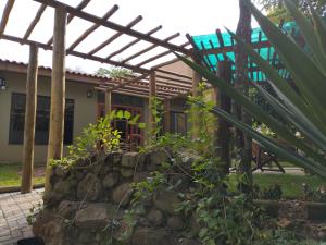 a house with a wooden pergola and a stone wall at Pousada Verde Perto - Demétria in Botucatu