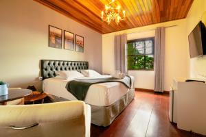 a bedroom with a bed and a table and a couch at Pousada Casa de Campos Guest House by Concavus in Campos do Jordão