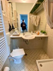 un homme prenant une photo d'une salle de bains avec toilettes et lavabo dans l'établissement Athina's Nest, à Athènes