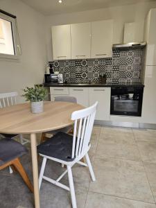 a kitchen with a wooden table and white cabinets at 200m de la plage en centre ville au calme in Le Grau-du-Roi